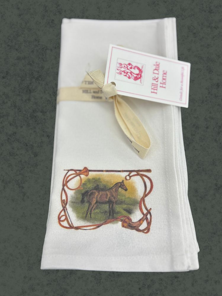 White cotton cloth napkin folded and tied with a Hill & Dale Home ribbon, featuring a hand-illustrated horse framed by hunting horns, reins, and crop.