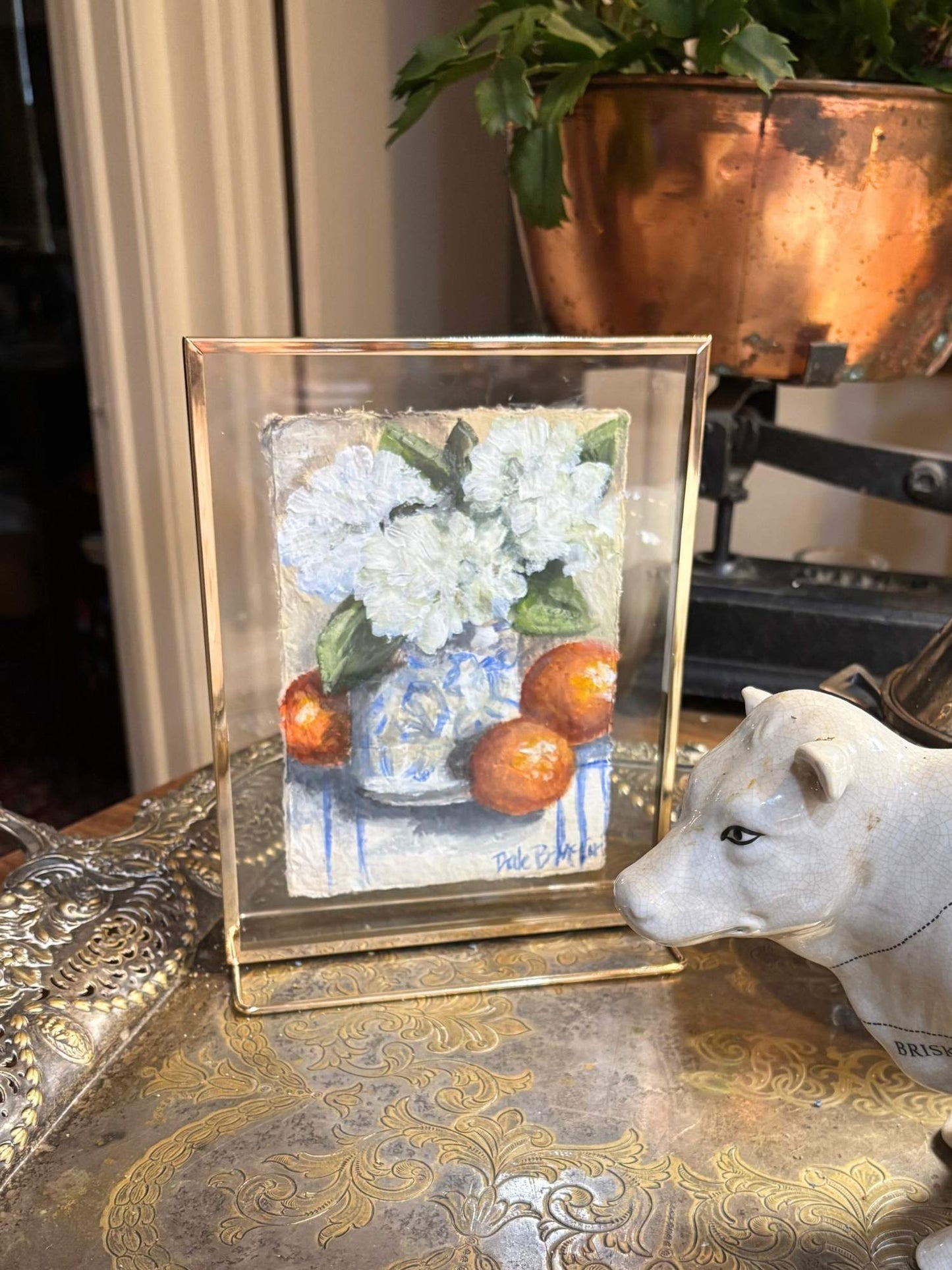 Original acrylic still life of white florals and orange citrus in a blue and white vase, painted on handmade Lokta paper and displayed in a brass floating glass frame.