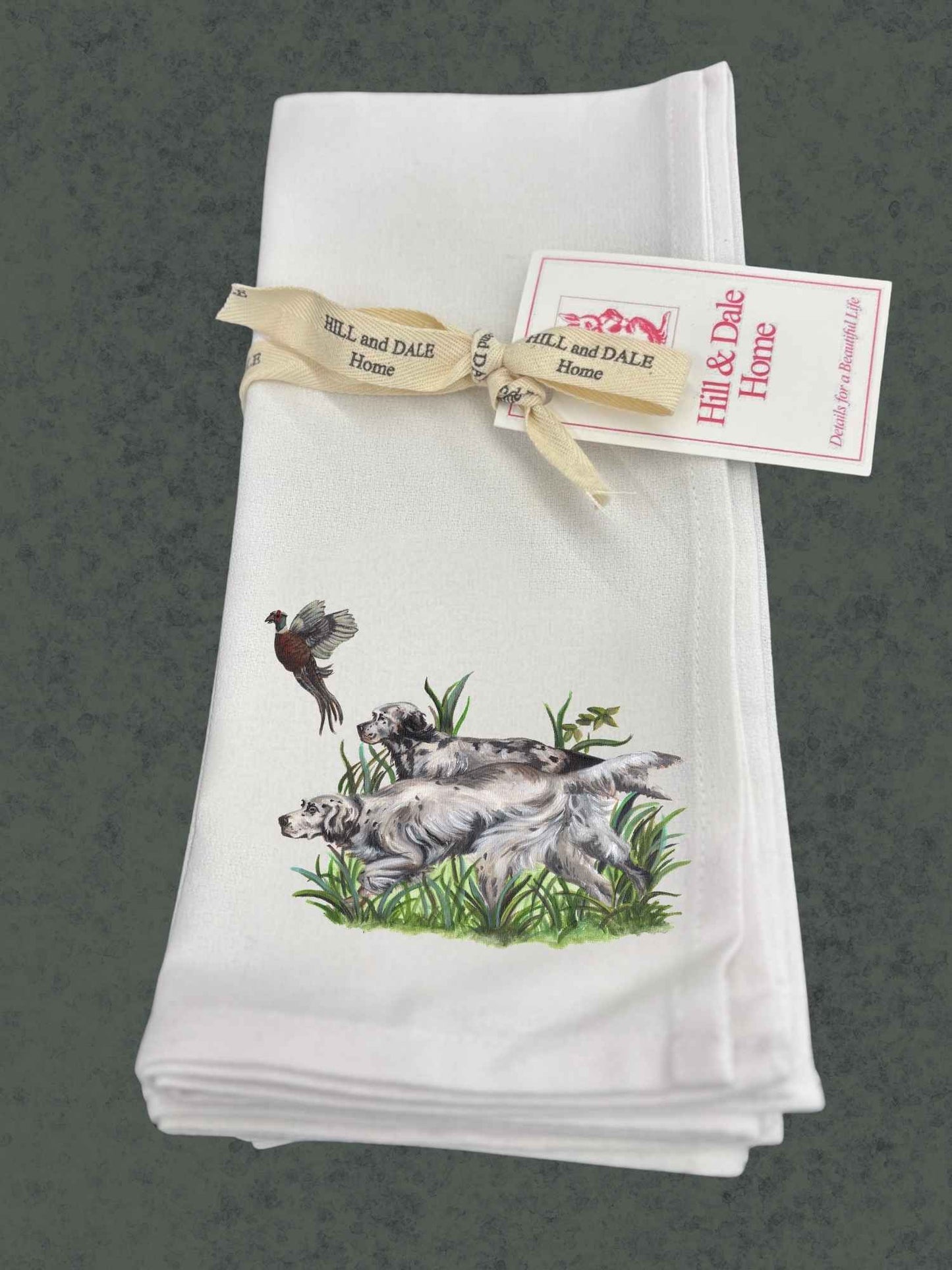 Set of white Hill & Dale Home bird dogs cloth napkins tied with branded ribbon, featuring artwork of two English setters in grass with a flying pheasant above.