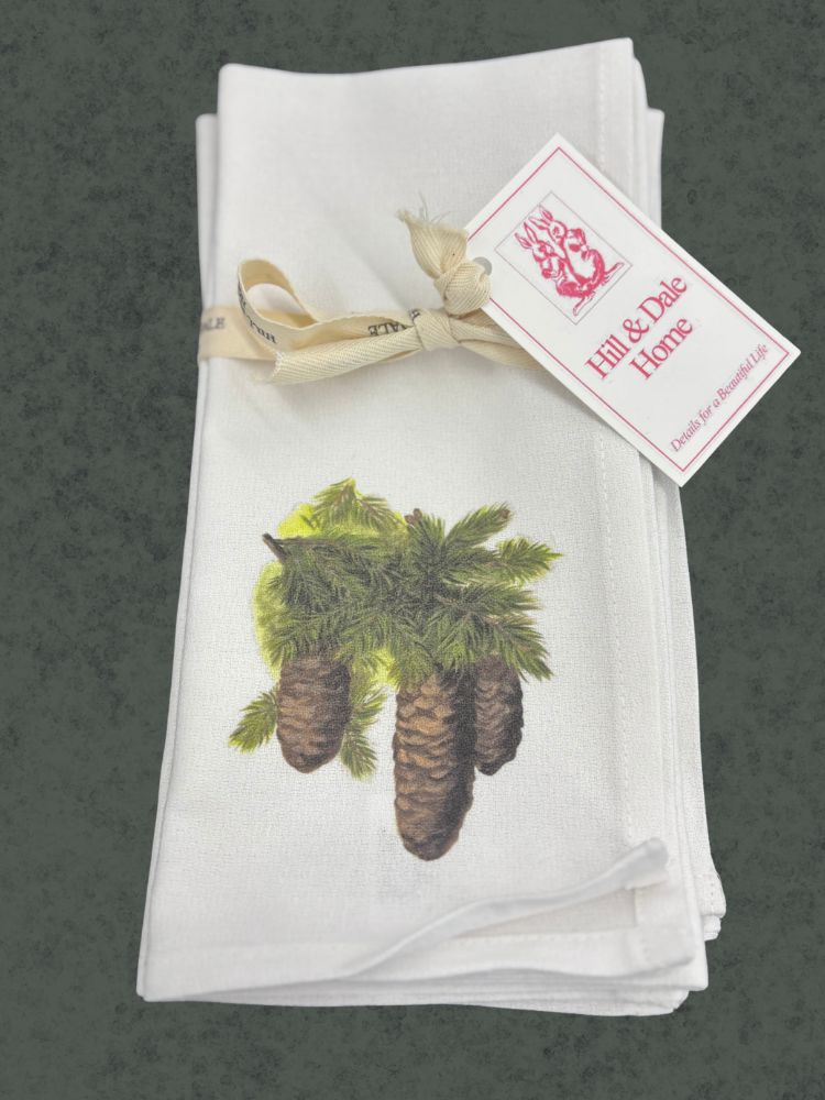 Set of cloth napkins tied with a Hill & Dale Home ribbon, featuring a detailed illustration of three pinecones with lush green needles on a white background.