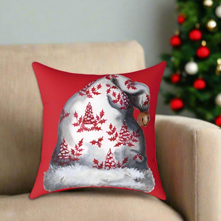 Photo of a red throw pillow with a Santa hat design on a beige couch with a Christmas tree in the right corner