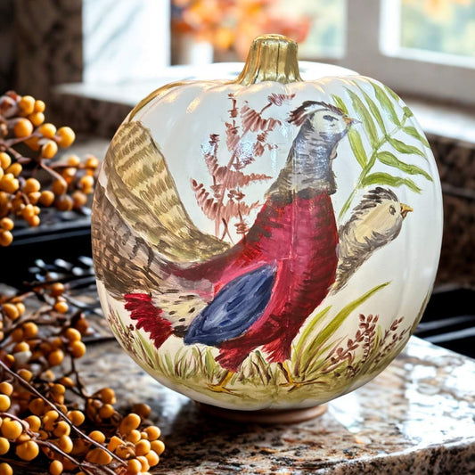 Hand-painted pumpkin featuring a pair of ornamental pheasants in rich red, gold, and navy hues, surrounded by fall foliage and delicate greenery.