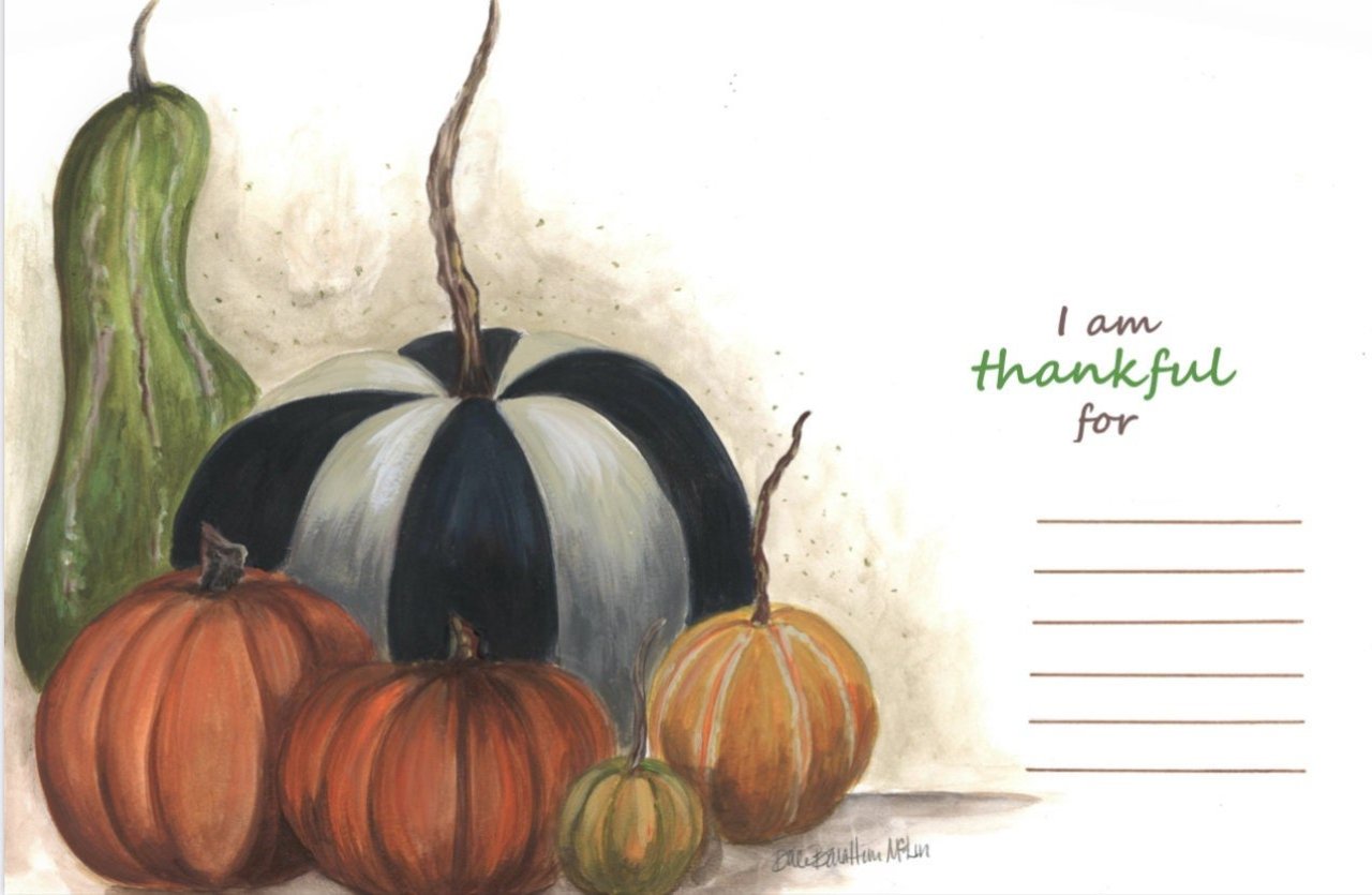 Up close photo of a Thanksgiving paper placemat. The design includes pumpkins, the words "I am thankful for" and lines underneath to write what you're grateful for. 