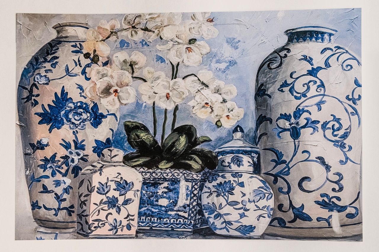 Photo of a paper placemat on a white background showcasing chinoiserie vases and white orchids