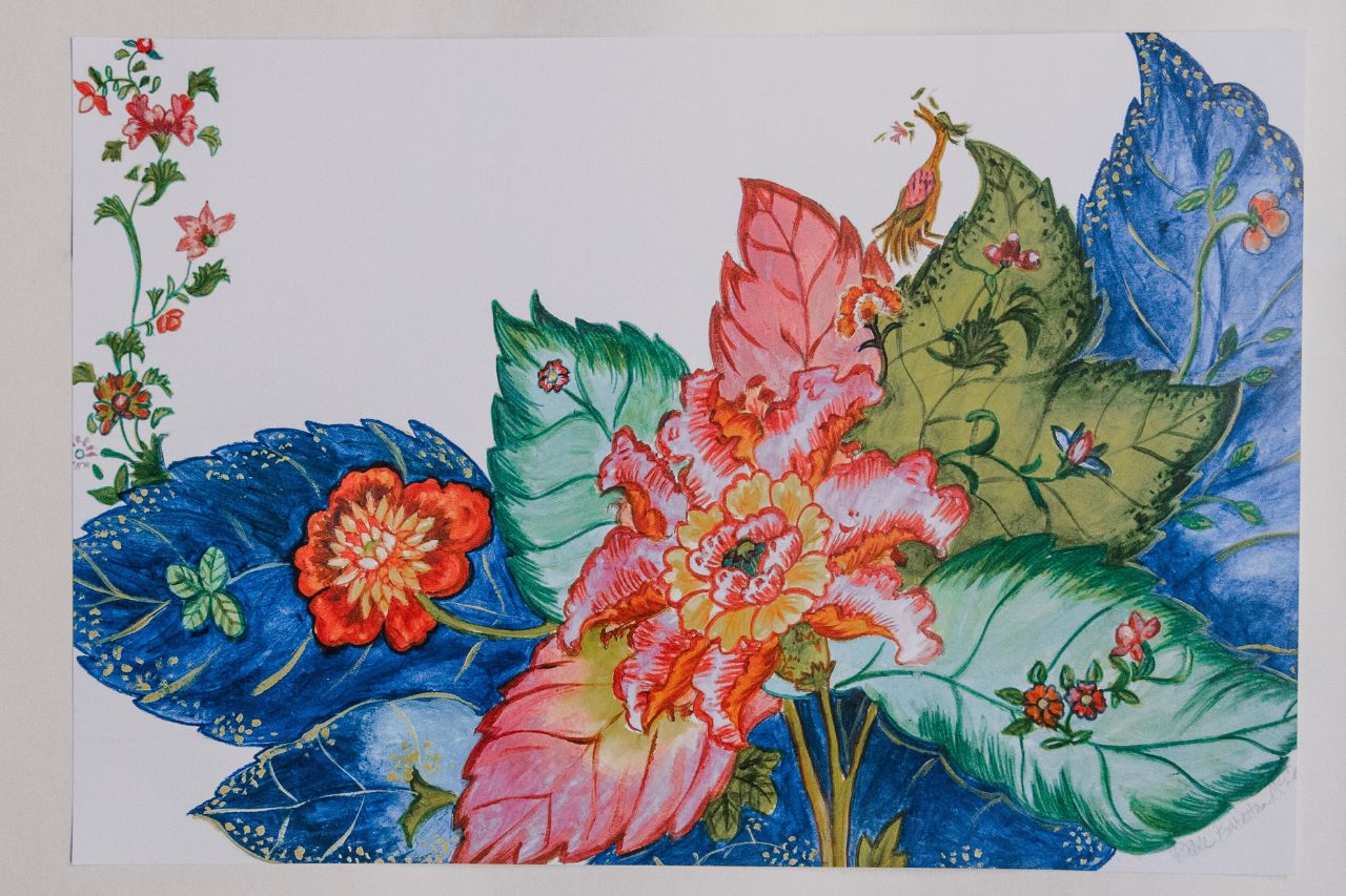 Photo of a paper placemat against a white background. The placemat features a vibrant tobacco leaf-patterned design