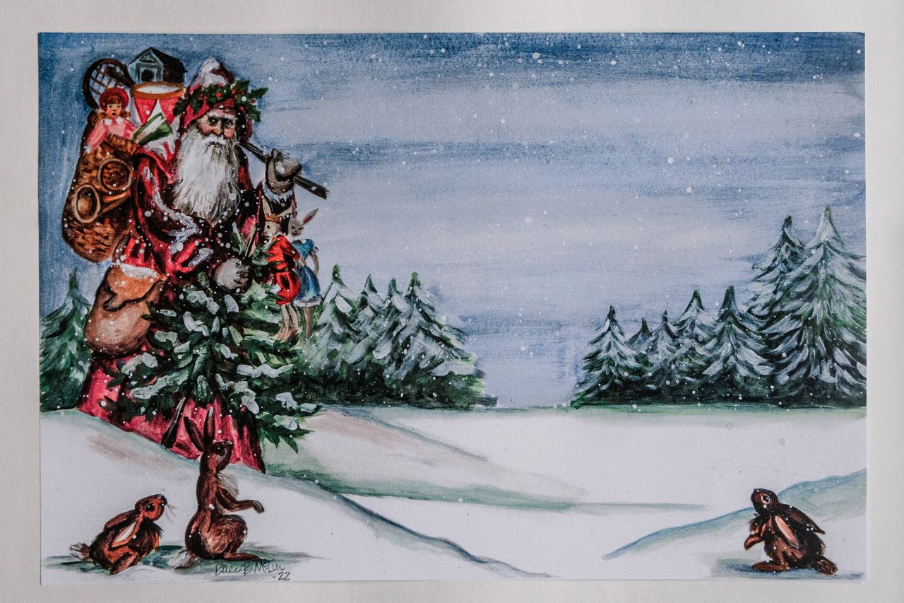 Photo of a paper placemat against a white background. The placemat artwork features a festive mountain Santa carrying gifts through the snowy landscape