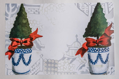 Photo of a paper placemat against a white background. The placemat features a Christmas topiary design against a chinoiserie background.