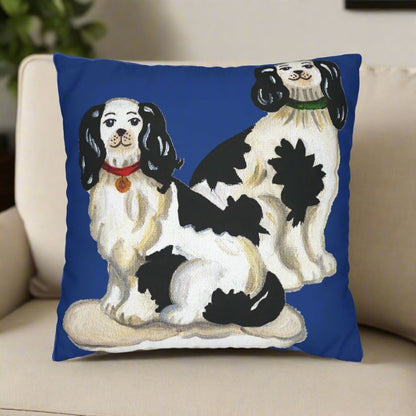 Photo of a canvas pillow featuring two Staffordshire dogs (white and black) with a blue background sitting on a beige chair