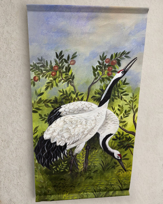 Two white and black red-crowned cranes stand among apple trees with soft green foliage and a watercolor-style sky in the background on a vertical wall hanging.