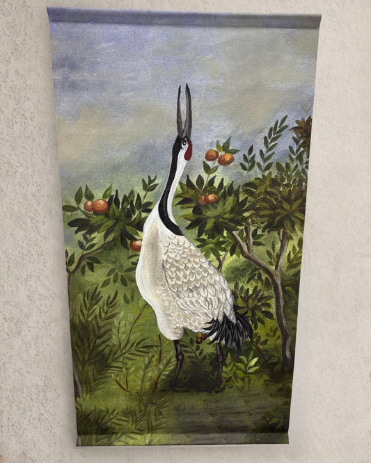 A single red-crowned crane with its beak lifted stands tall among leafy branches and orange fruits on a green and blue painted fabric wall hanging.