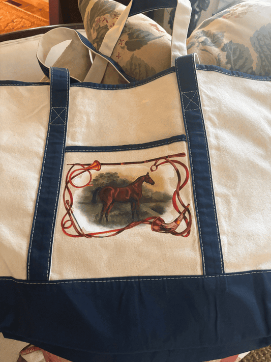 Canvas tote with navy trim and design of a chestnut horse standing in a field, framed by flowing reins and hunting horns.