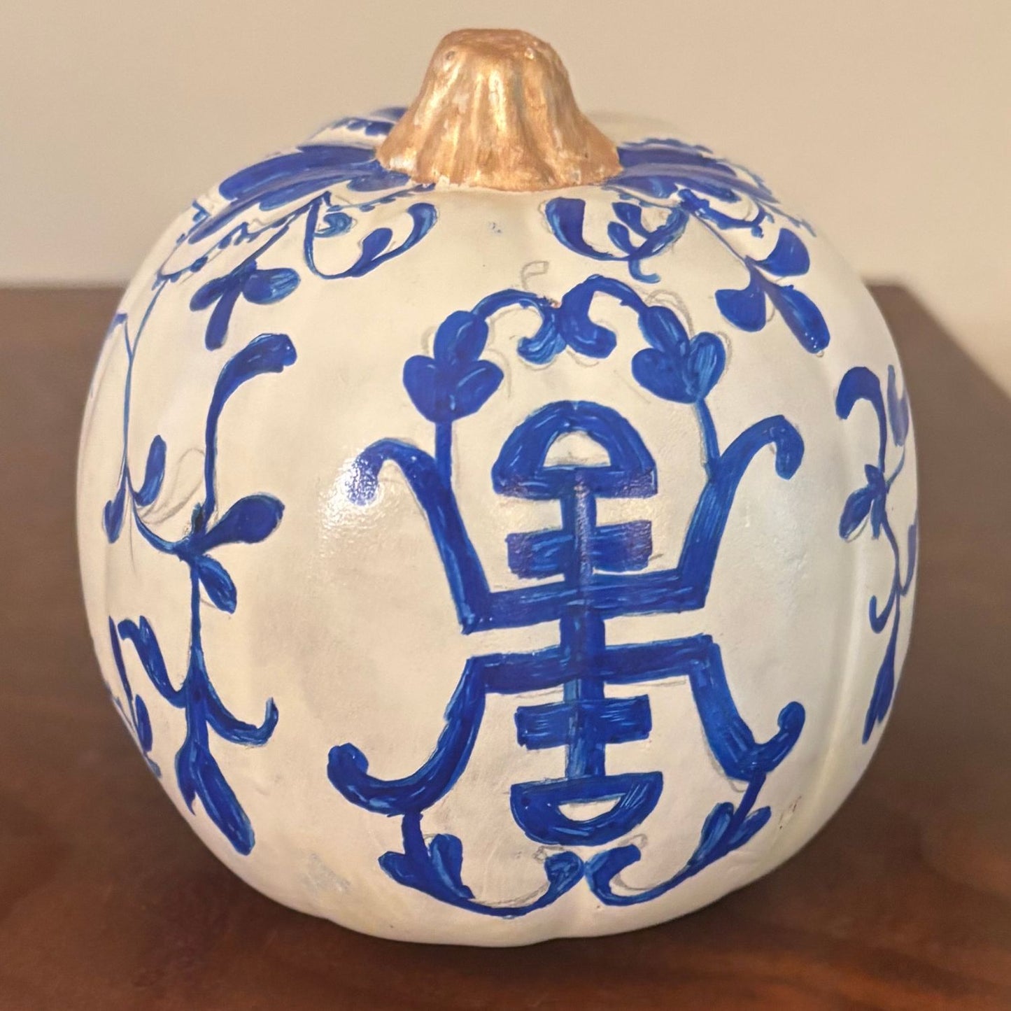 White hand-painted pumpkin with a cobalt blue porcelain-style motif and metallic gold stem. A graceful addition to your fall decor.
