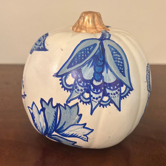 Hand-painted white pumpkin featuring intricate blue chinoiserie floral designs with a gold-painted stem.