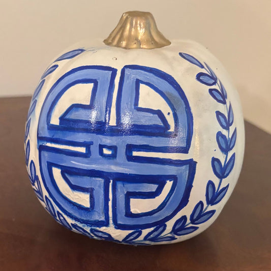 White pumpkin featuring a circular blue longevity-inspired symbol framed by delicate blue leafy garlands, topped with a gold-painted stem.