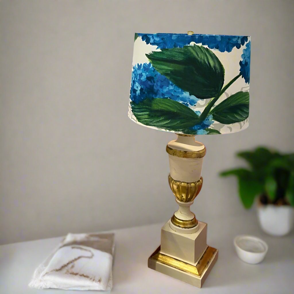 Photo of a gold lamp with a lampshade featuring a design with blue hydrangeas