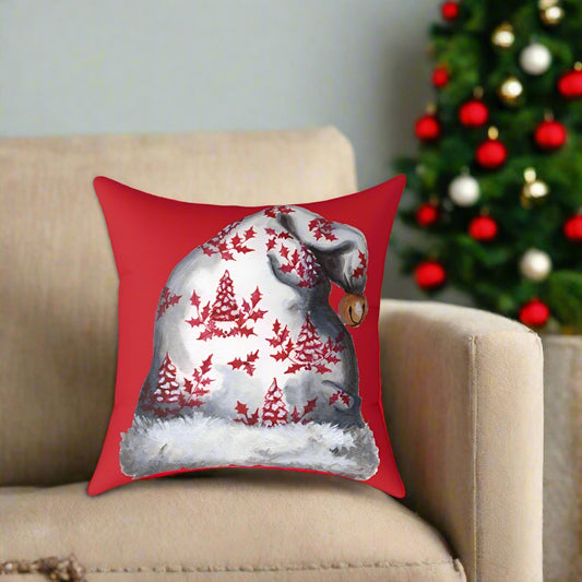 Photo of a red throw pillow with a Santa hat design on a beige couch with a Christmas tree in the right corner