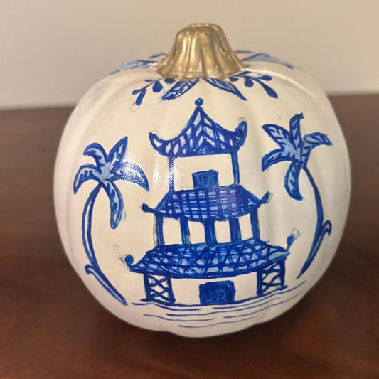 Hand-painted white pumpkin featuring a blue chinoiserie temple design with palm trees and a gold stem.