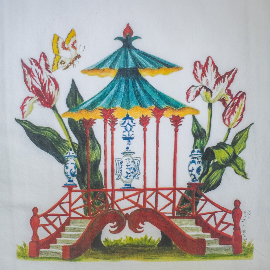 Close up photo of artwork detail on a white tea towel with a red pagoda design surrounded by butterflies and traditional blue and white porcelain