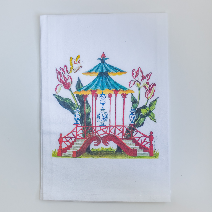 Photo of a white tea towel with a red pagoda design surrounded by butterflies and traditional blue and white porcelain